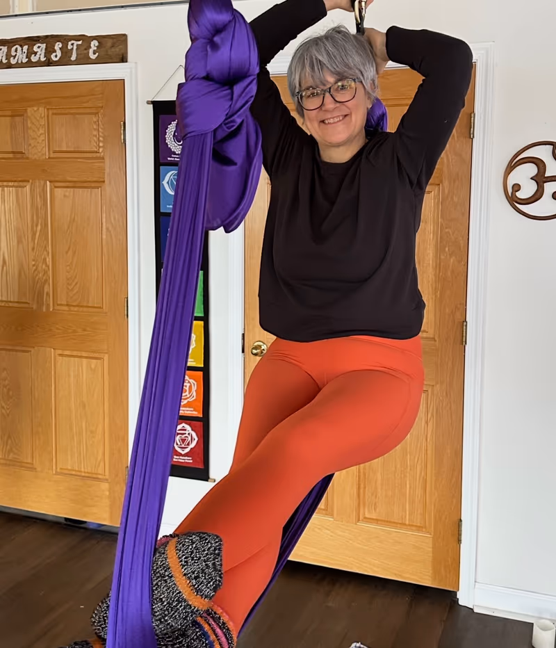 instructor smiling in an aerial yoga hammock at the Hampstead studio